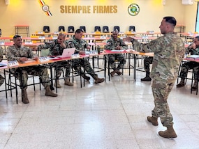 Military personnel sit at desks.