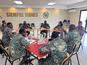 Military personnel sit at desks.