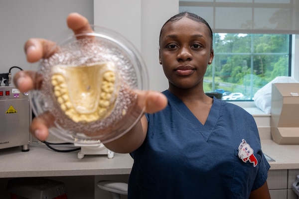 U.S. Navy Hospital Corpsman 3rd Class Niyona Gibbs, a dental technician with 2nd Dental Battalion, 2nd Marine Logistics Group, and a native of Bayboro, North Carolina, holds a dental mold while posing for a photo at Marine Corps Base Camp Lejeune, North Carolina, May 12, 2025. Gibbs was selected as the 2nd MLG Warrior of the Week by her leadership for her proficiency, maturity, and dedication to her job as a dental technician.  Her impact during exercise Joint Viking was remarkable where she assisted in the care of 200 patients and provided 75 hours of medical coverage during six training evolutions for the exercise. Each week, 2nd MLG recognizes one outstanding Marine or Sailor that goes above and beyond in their duties and embodies the qualities of an outstanding service member. (U.S. Marine Corps photo by Sgt. Alfonso Livrieri)