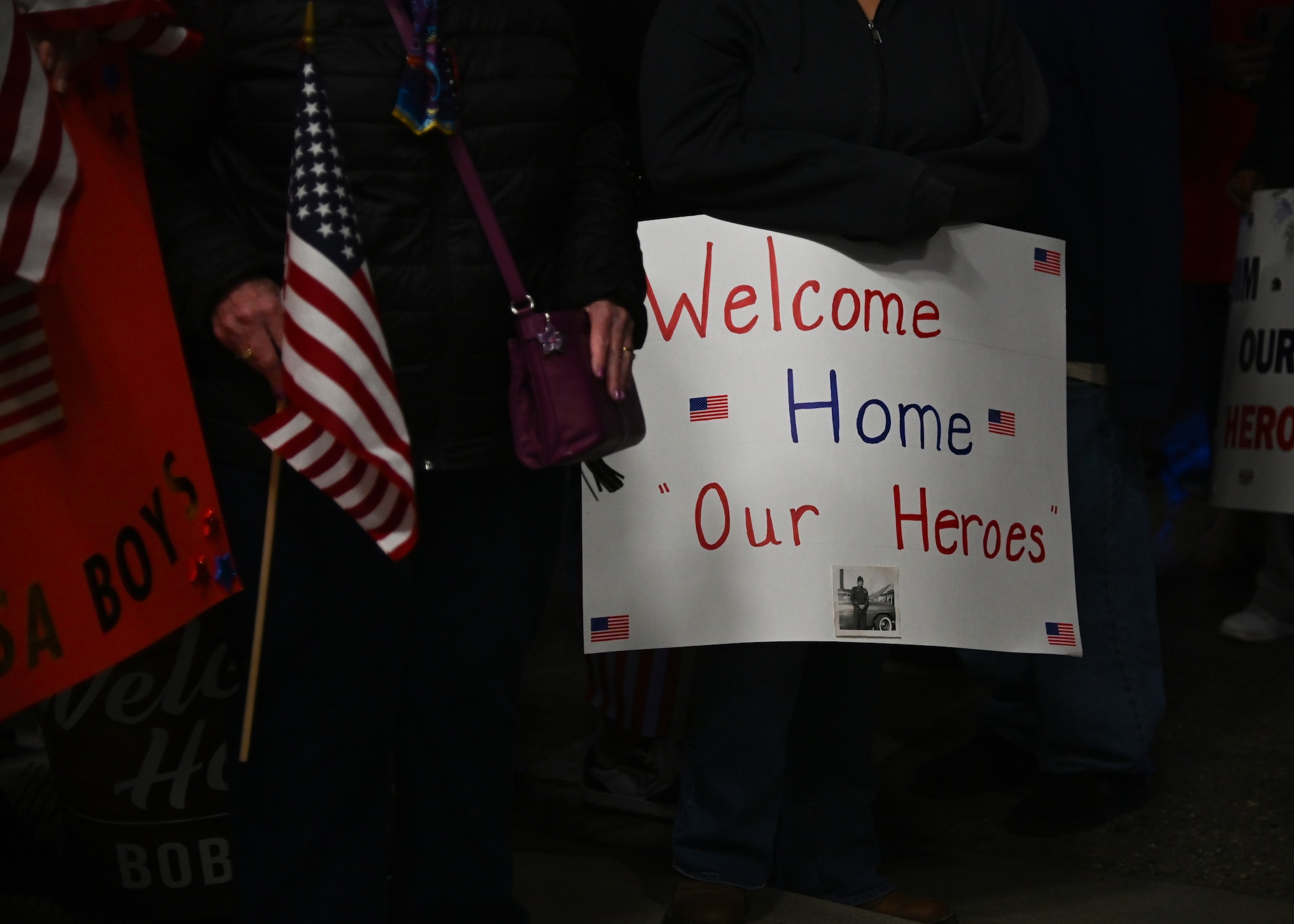 veterans in red white and blue and military members all cheering and welcoming home veterans from the honor flight