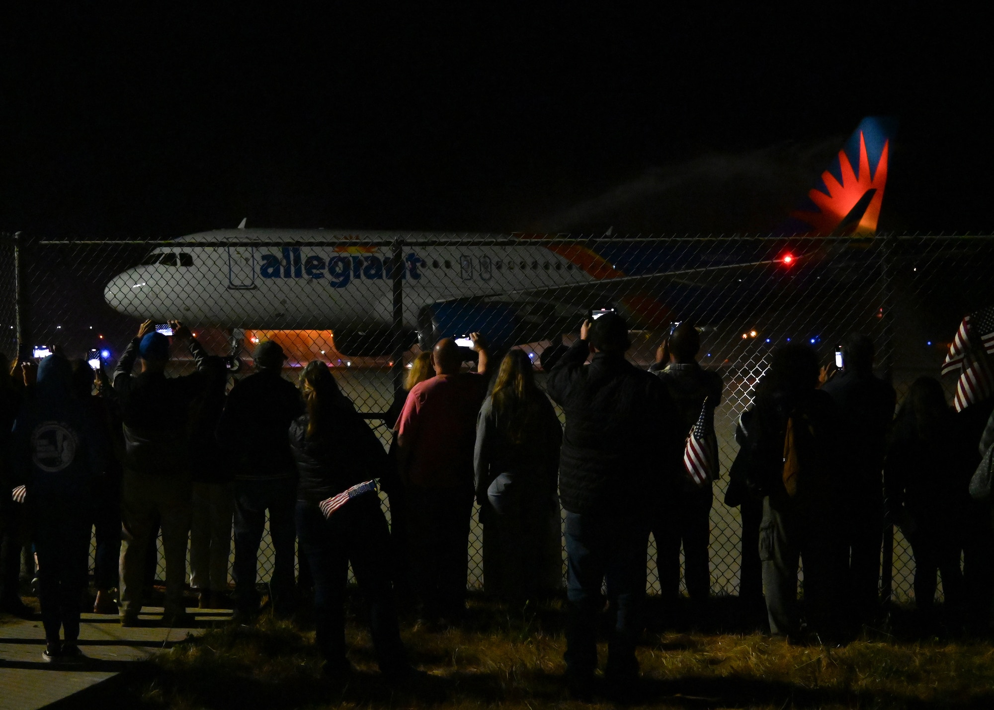 veterans in red white and blue and military members all cheering and welcoming home veterans from the honor flight