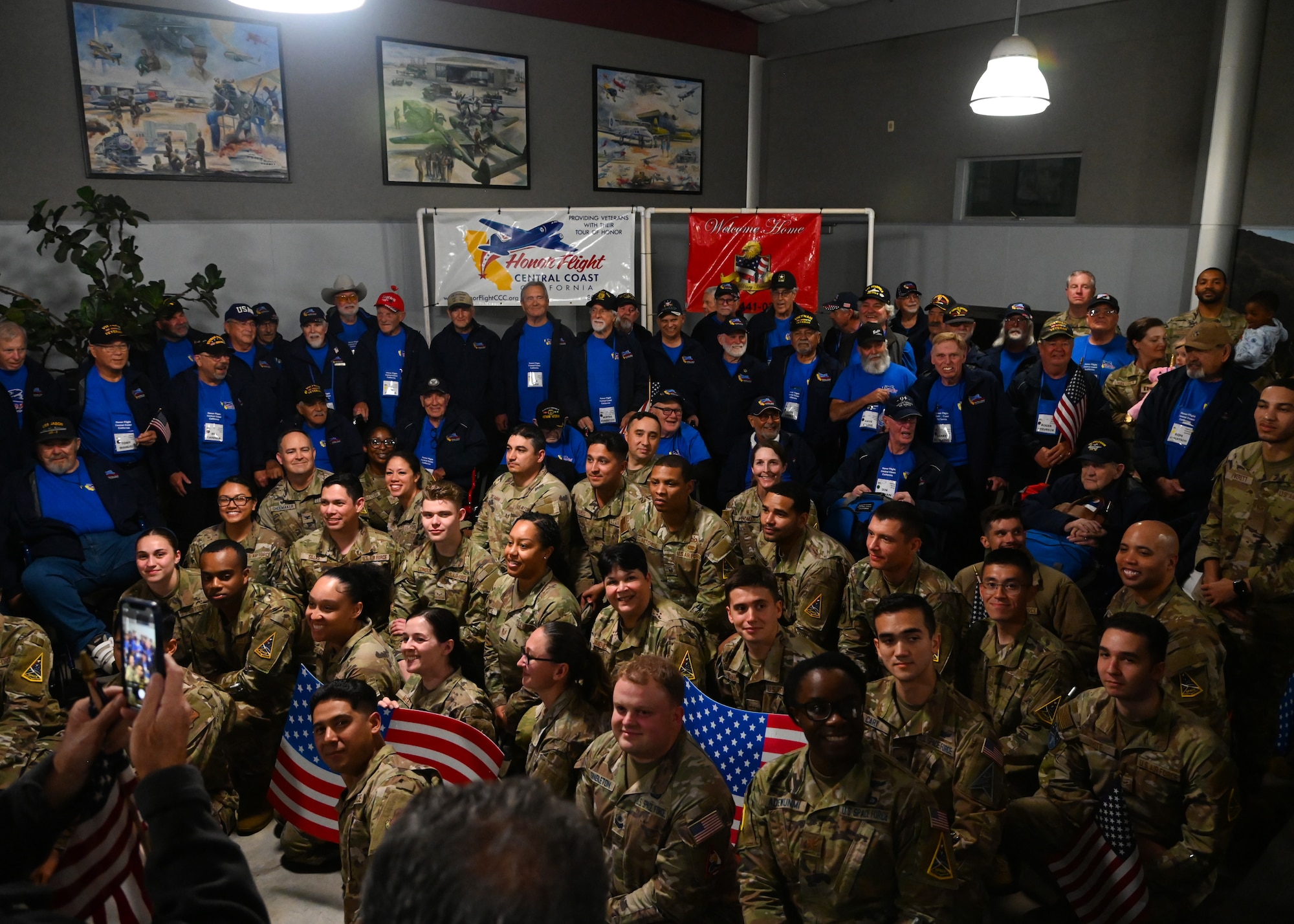 veterans in red white and blue and military members all cheering and welcoming home veterans from the honor flight