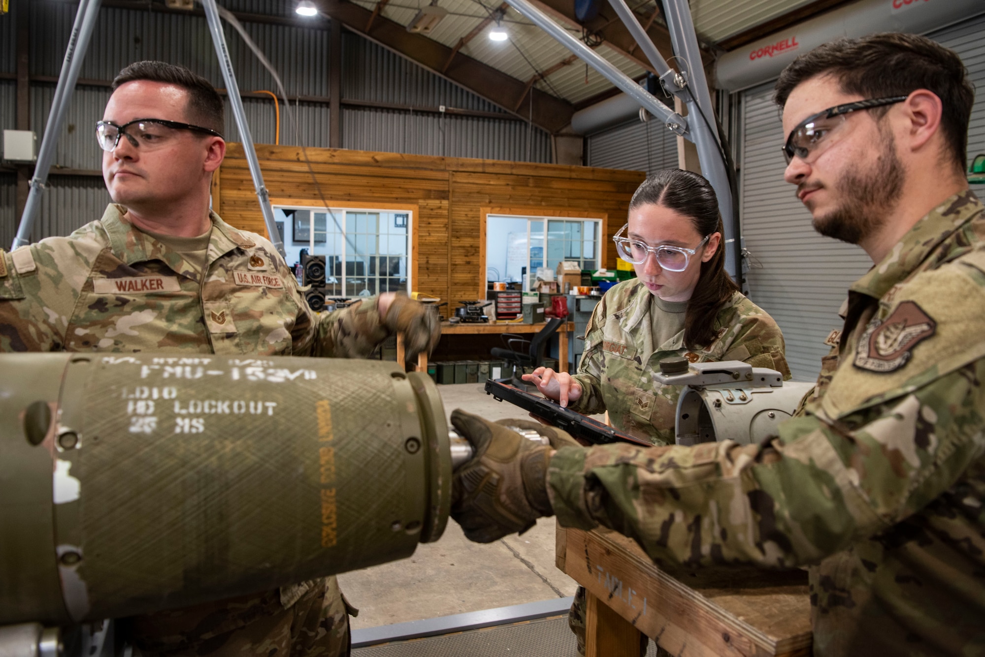U.S. Air Force Tech. Sgt. Joshua Walker, 51st Munitions Squadron conventional maintenance supervisor, left, and Airman 1st Class Niko Guaglianone, 51st MUNS conventional maintenance crew chief, assemble a munition while Senior Airman Quinn Corgiat, 51st MUNS conventional maintenance inspector reviews technical orders at Osan Air Base, Republic of Korea, May 14, 2025.