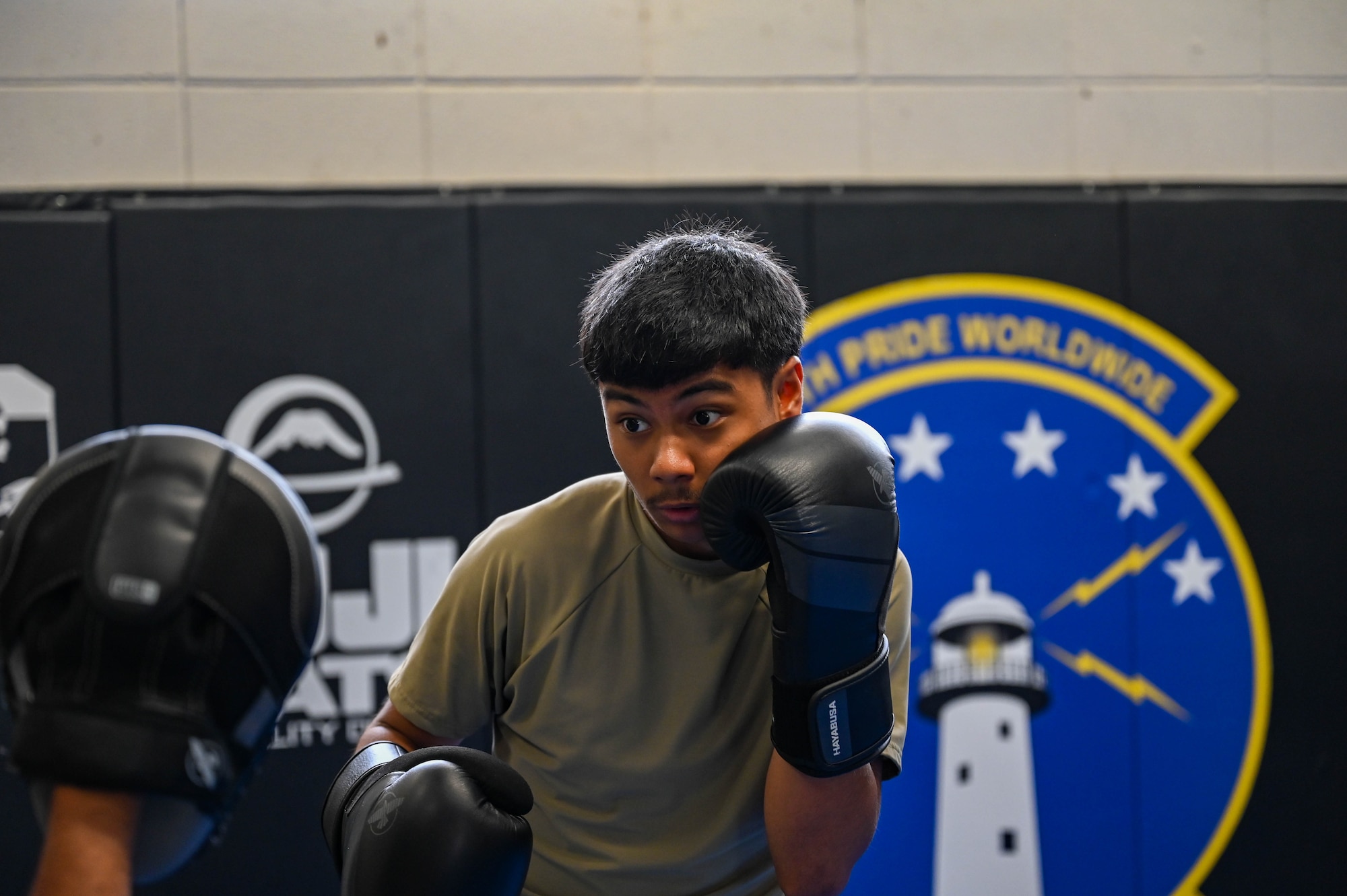 An Airman wearing a military uniform and boxing gloves during the combatives training at the Expeditionary Communications Roundup.