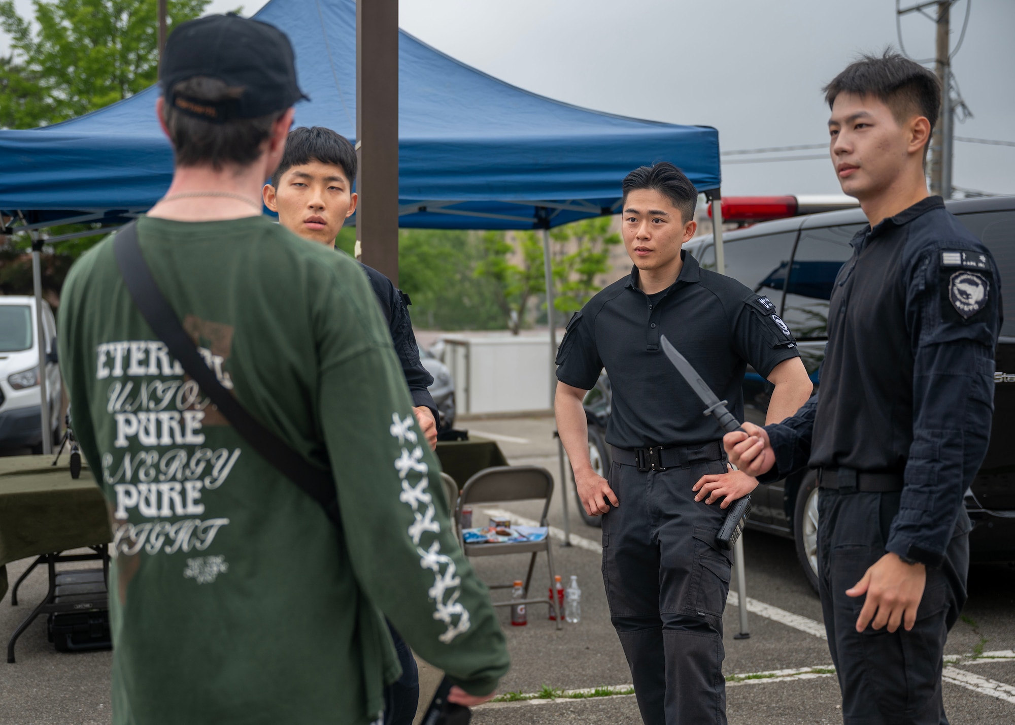 Republic of Korea Air Force Korean Military Police explain self defense to an attendee during the Law Enforcement Display for the 2025 National Police Week at Osan Air Base, Republic of Korea, May 15, 2025. ROKAF Military Police train with edged-weapon scenarios to sharpen their self-defense capabilities, ensuring they can respond with precision and control against armed threats. (U.S. Air Force photo by Senior Airman Sarah Williams)