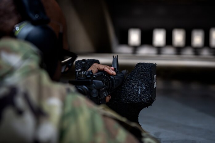 An Airman aims down the iron sight of an M4 carbine.