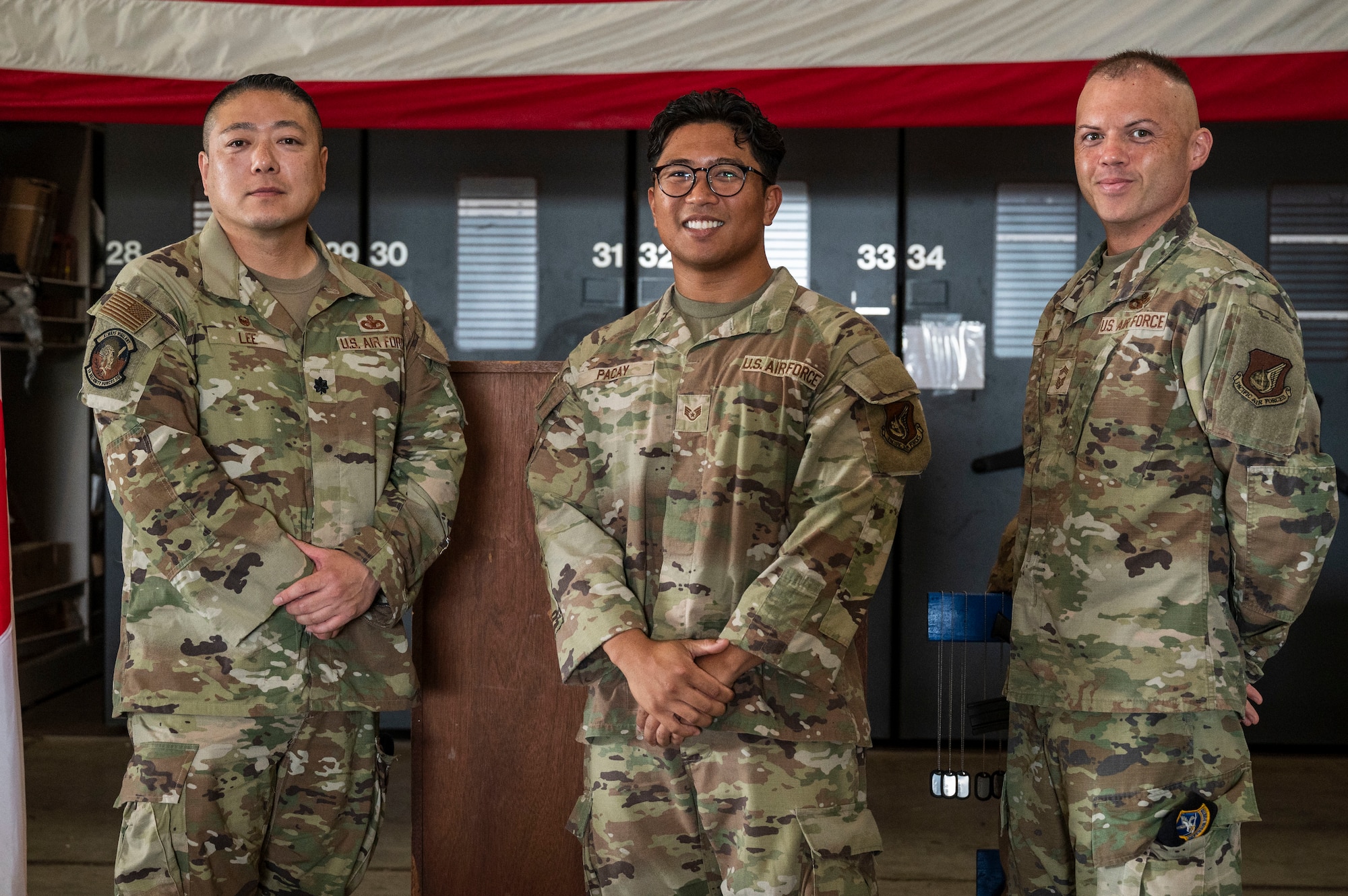 U.S. Air Force Lt. Col. Min Lee, left, 18th Security Forces Squadron commander, and Chief Master Sgt. Nicholas Wong, right, 18th Security Forces Squadron command Chief, pose for a photo with Staff Sgt. Clark Pacay, 67th Fighter Generation Squadron dedicated crew chief, during the police week closing ceremony at Kadena Air Base, Japan, May 16, 2025