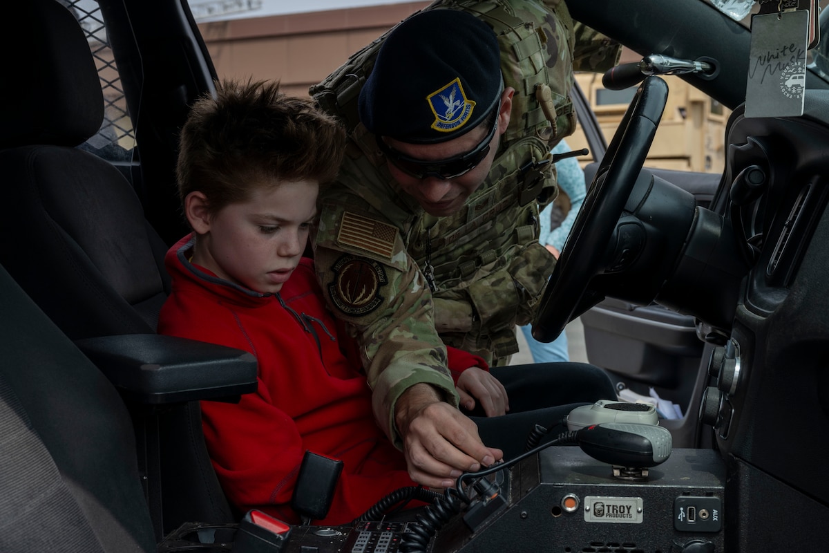 U.S. Air Force Staff Sgt. Anthony De La Cruz, right, 35th Security Forces Squadron unit deployment manager, shows an attendee how to use a radio during a Police Week demonstration.