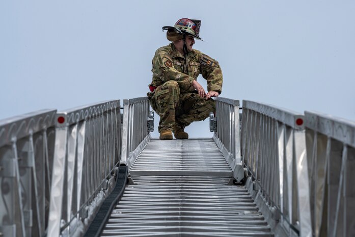 U.S. Air Force Staff Sgt. Thomas Hyde, 35th Civil Engineer Squadron firefighter, kneels at the top of a fire ladder during a Police Week demonstration.