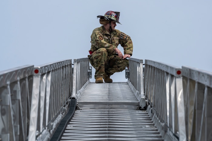 U.S. Air Force Staff Sgt. Thomas Hyde, 35th Civil Engineer Squadron firefighter, kneels at the top of a fire ladder during a Police Week demonstration.