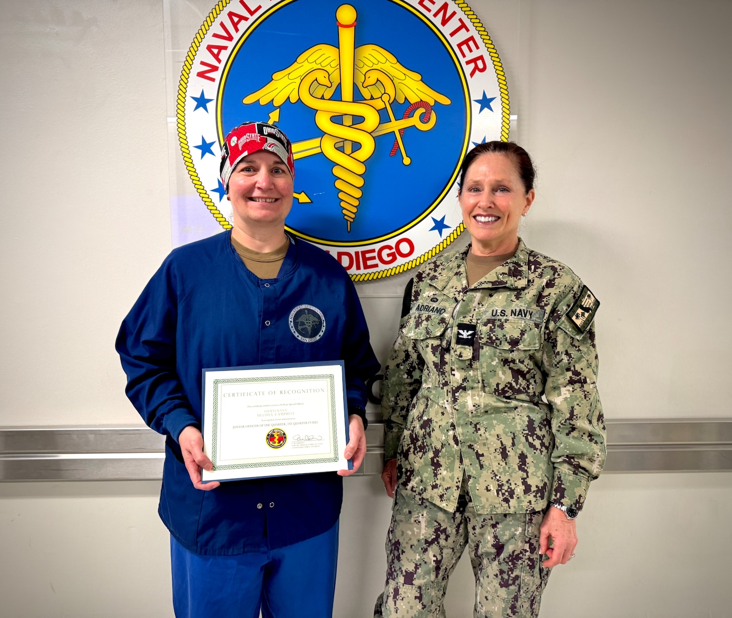 250512-N-WJ173-1001 SAN DIEGO (May 2025) – Lt. Melissa Campbell (left), Division Officer of the Main Operating Room at Naval Medical Center San Diego (NMCSD), is presented the Junior Officer of the Quarter award for Fiscal Year 2025, Quarter 1 by Capt. Elizabeth Adriano (right), NMCSD Director, 12 May, 2025.  Campbell was recognized for her outstanding leadership, oversight of more than 2,500 surgical cases, introduction of ENT robotics, and the launch of surgical telementoring—all of which contribute directly to enhanced warfighter readiness and surgical capability.  The mission of NMCSD is to provide a superior experience for our patients, staff, and warfighters. NMCSD employs more than 5,000 active-duty military personnel, civilians, and contractors in Southern California to deliver exceptional care afloat and ashore.