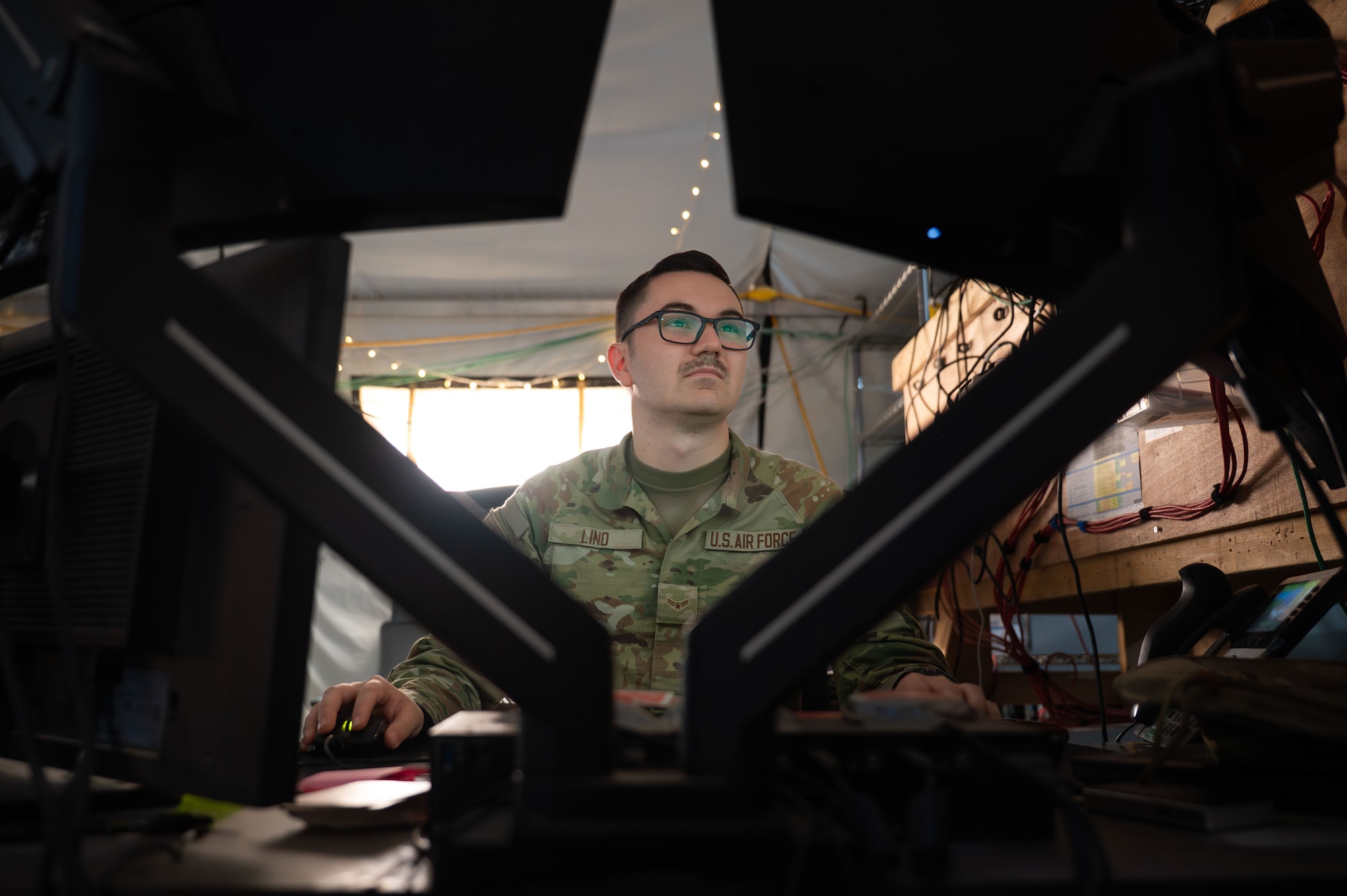 A man is seen from behind two computer screens.