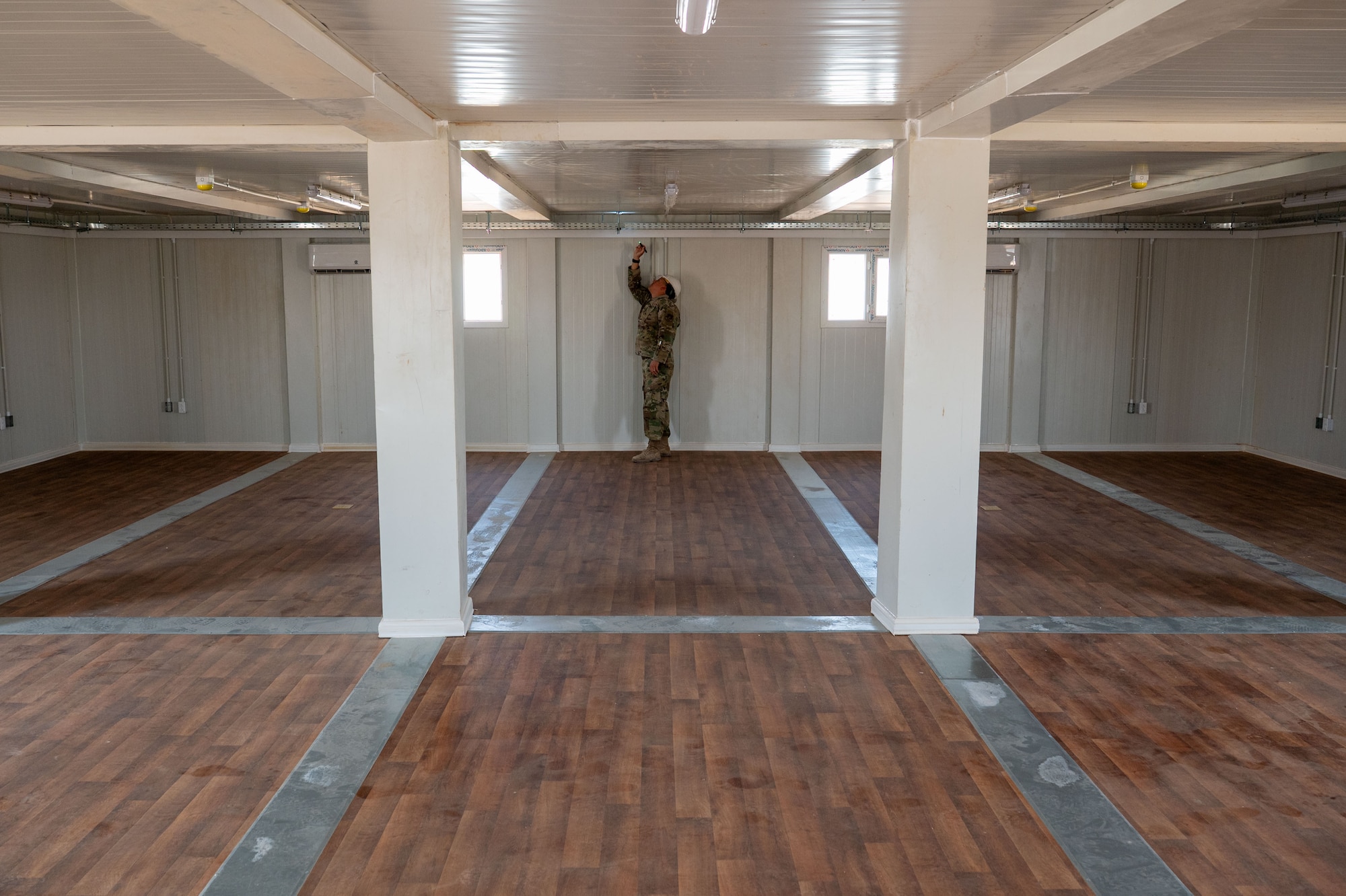 A man inspects a tray around the inside ceiling of a building.
