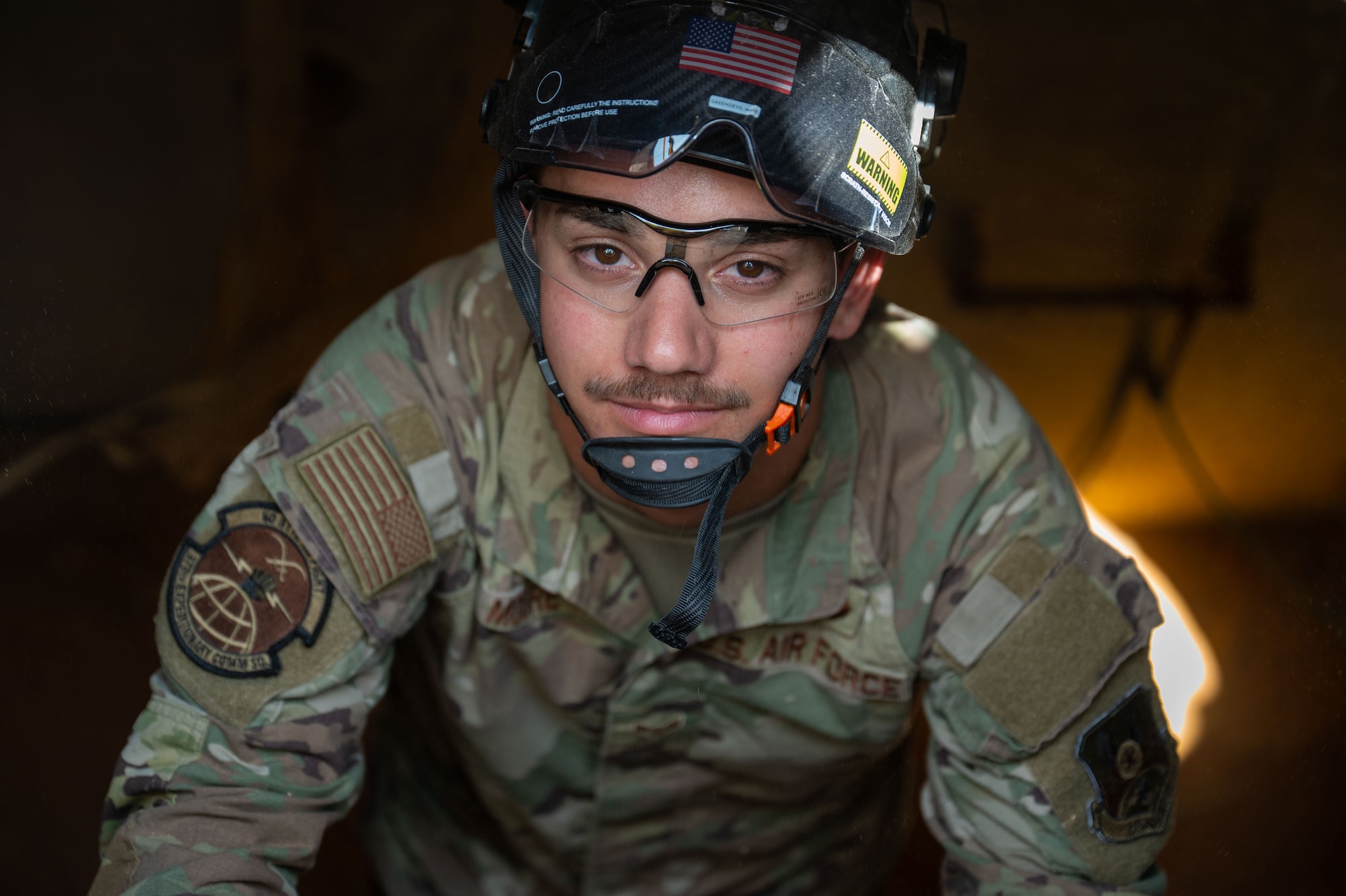 A man climbs out of an underground manhole.