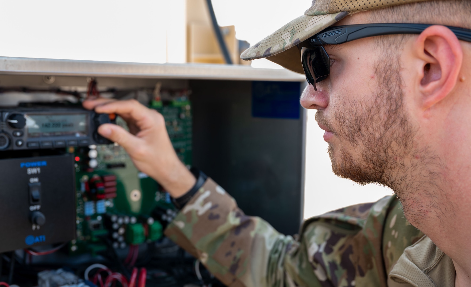 A man turns a knob on a radio within a control panel.