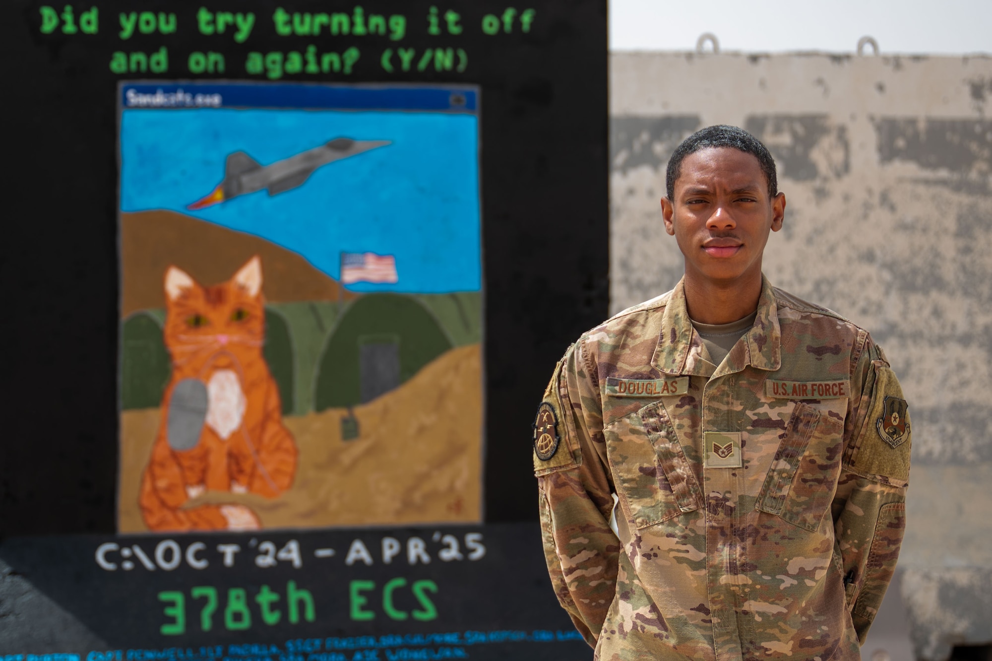 A man poses in front of a wall.