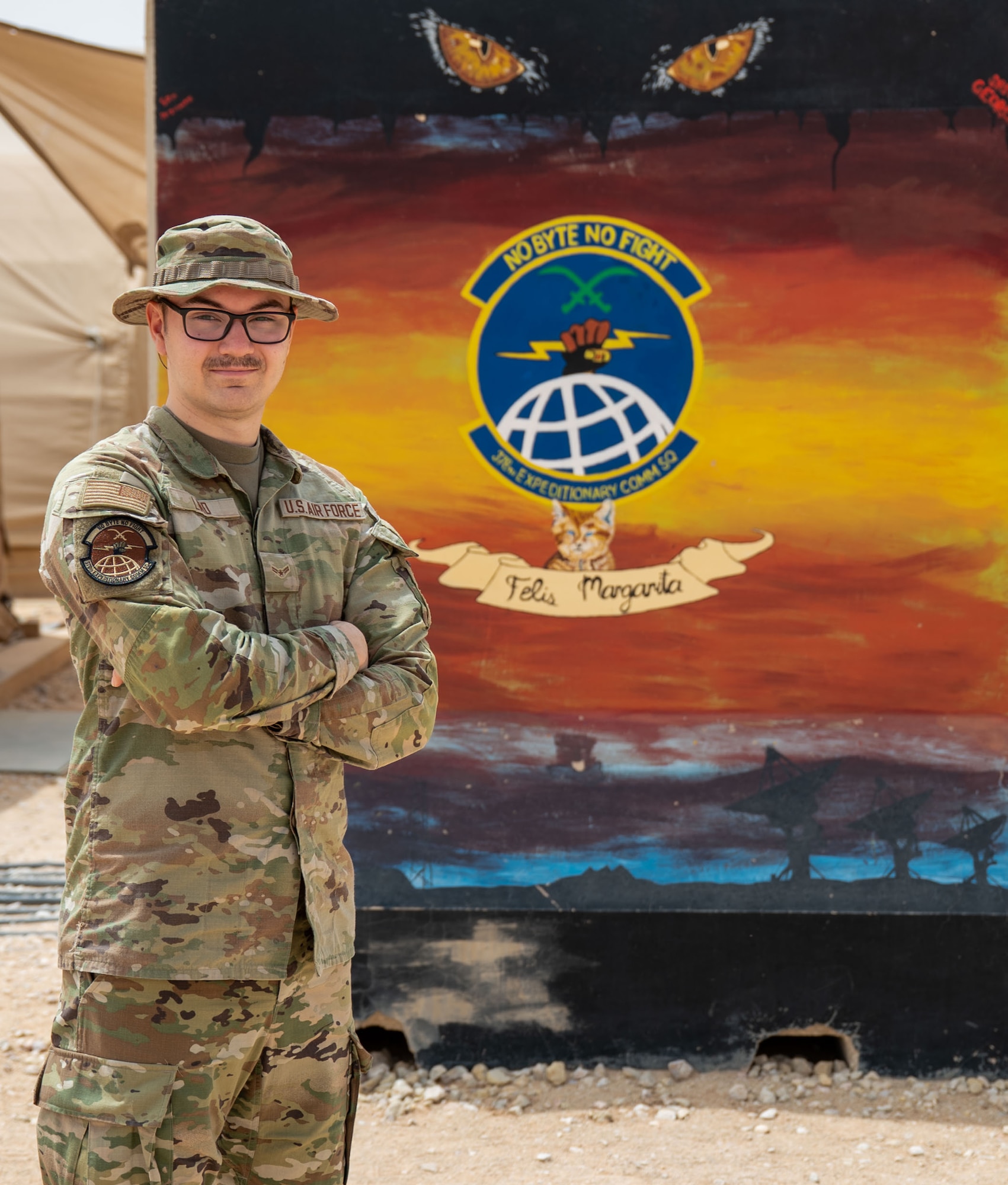 A man poses in front of a wall.