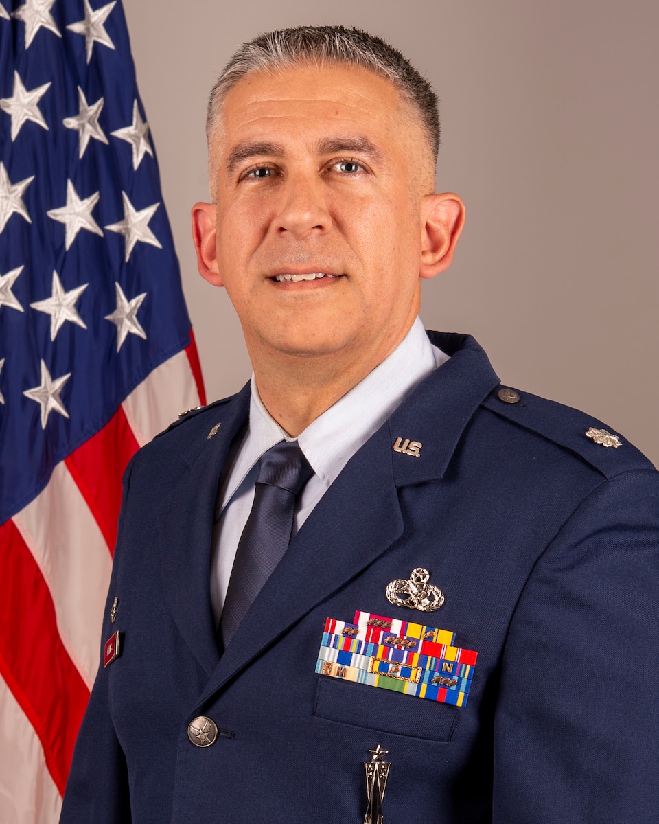 Lt. Col. John J. Valdes III, 434th Maintenance Group Commander, poses for official photo in front of U.S. flag.