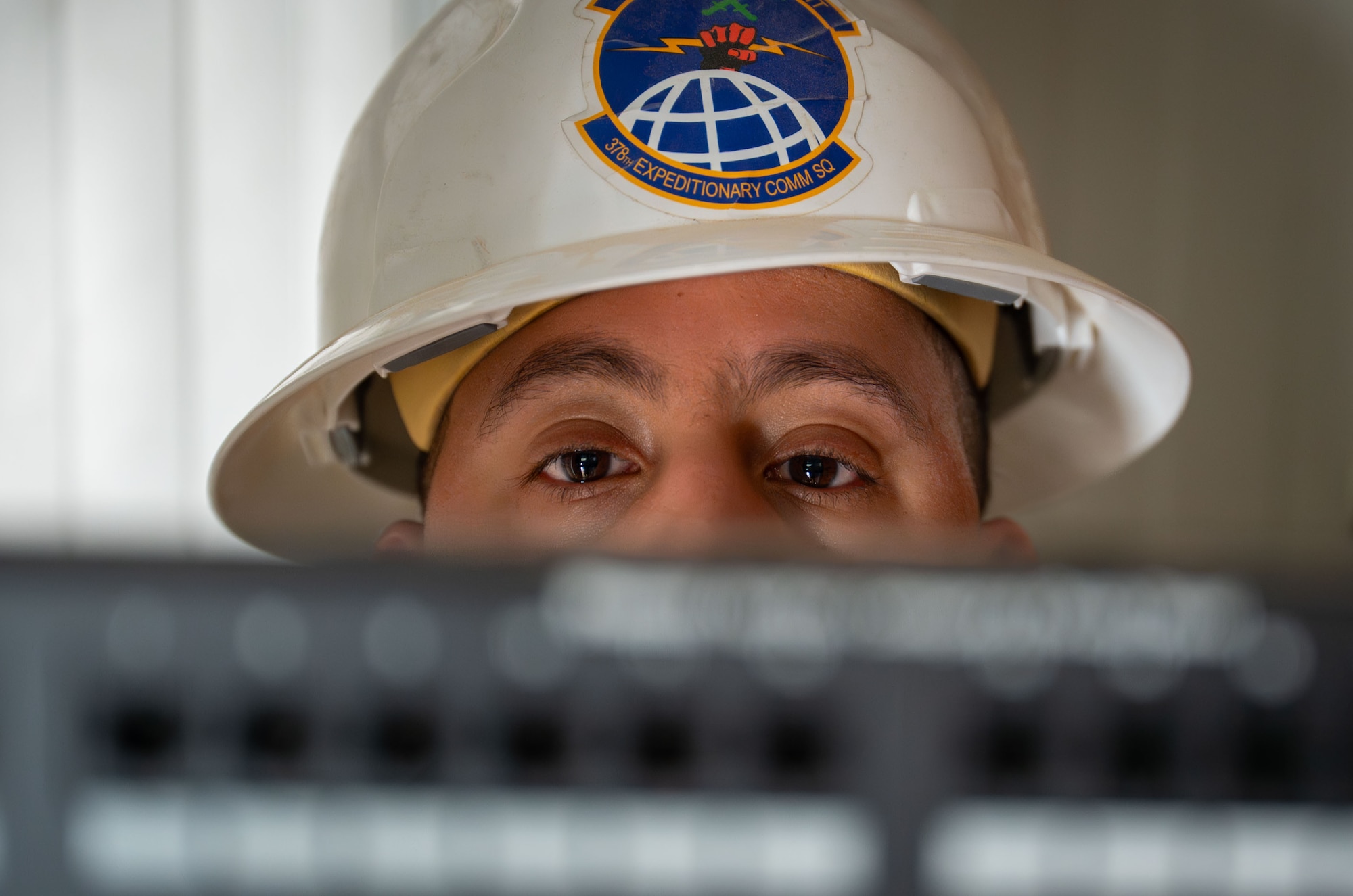 Part of a man's face is visible behind a blurred cable rack.