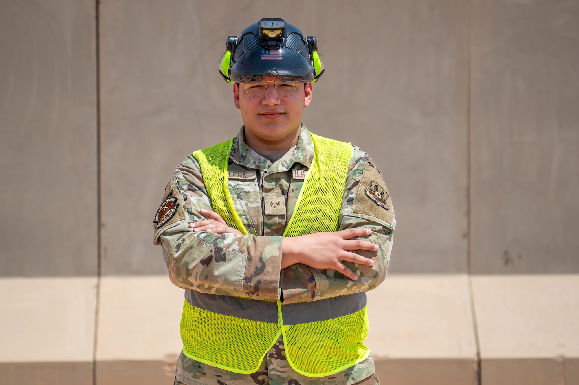 A man poses in front of a wall.