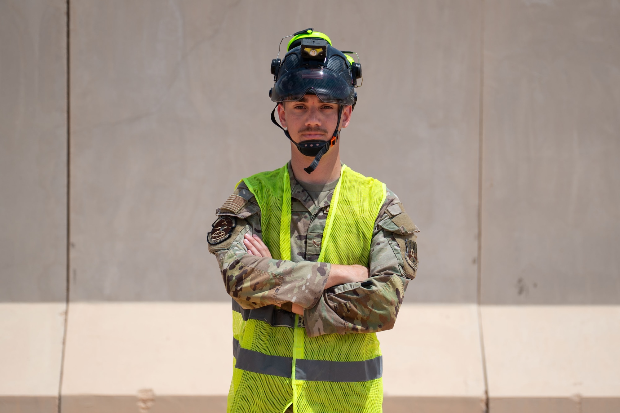A man poses in front of a wall.