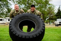 Two men lifting a huge tire wheel