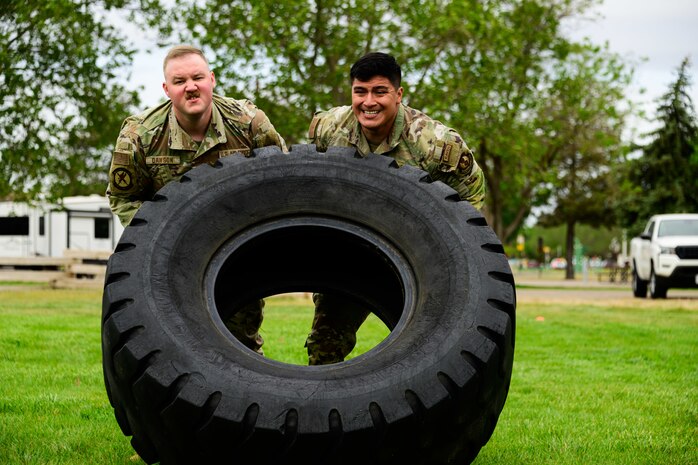 Two men lifting a huge tire wheel