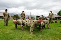 Four men performing a fire team pushup, pushups with their legs stacking upon each others.