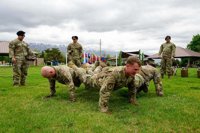 Four men performing a fire team pushup, pushups with their legs stacking upon each others.
