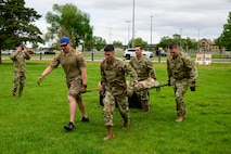Four men carrying a stretcher with a dummy