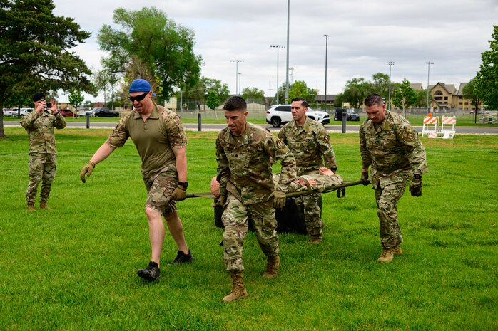 Four men carrying a stretcher with a dummy