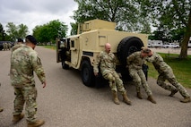 Three Airman pushing a humvee vehicle