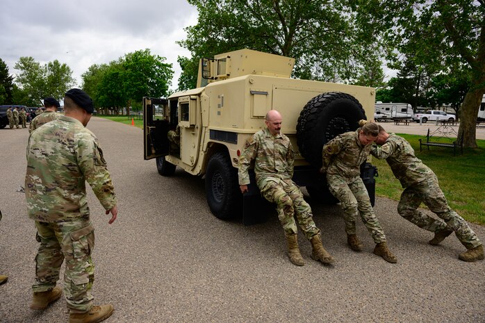 Three Airman pushing a humvee vehicle