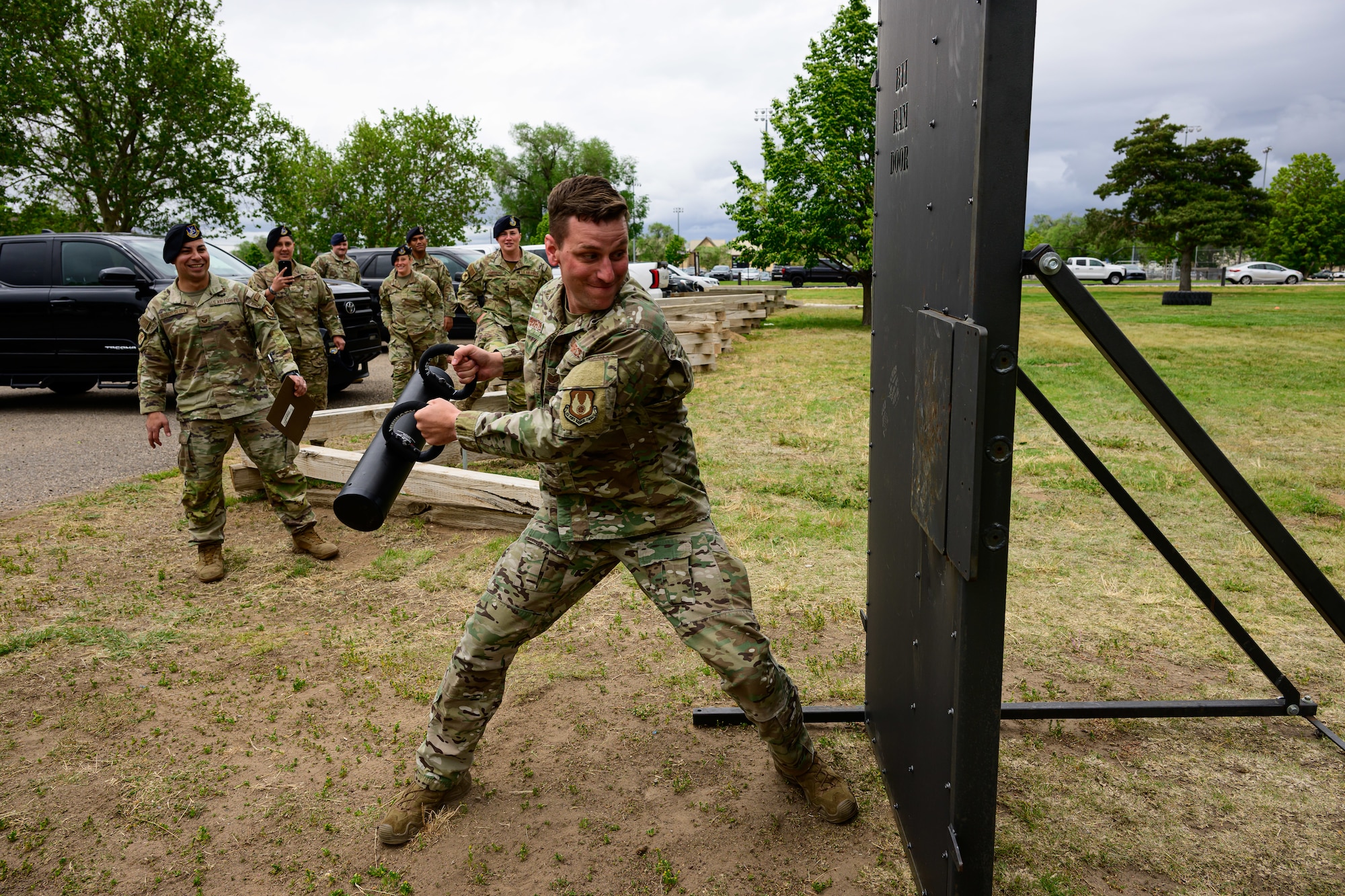 An airman with a steel rod breaching a door