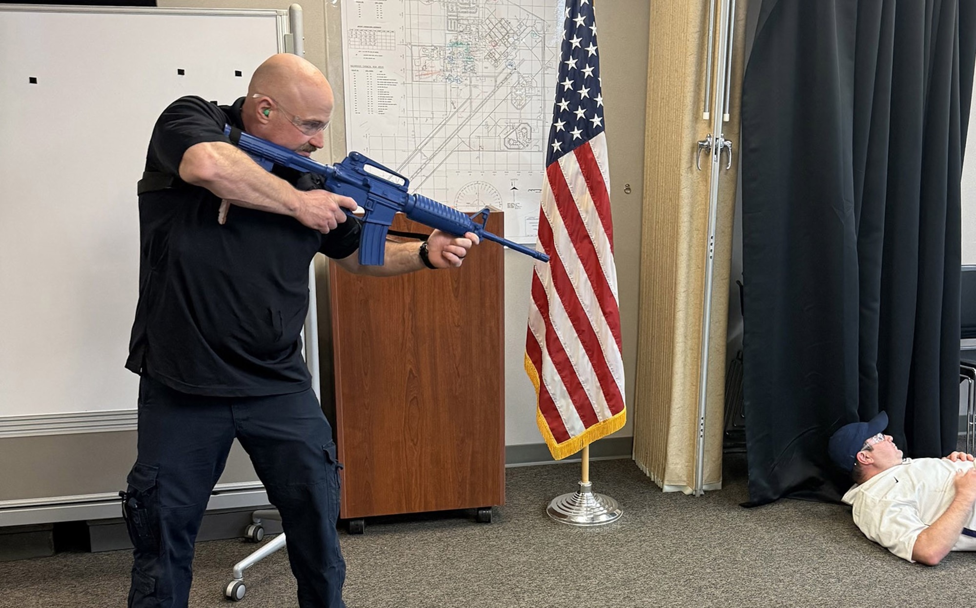 Law enforcement personnel aims training weapon at a person on ground