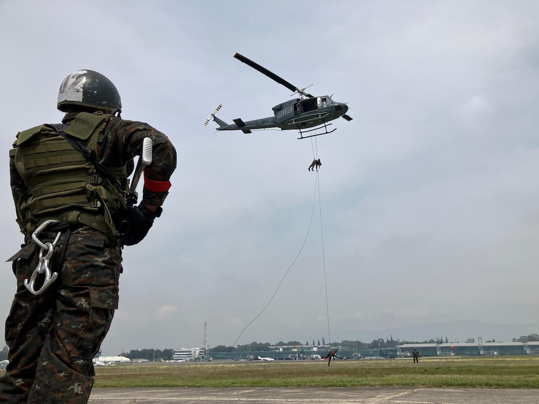A soldier stares up at a helicopter performing disaster relief training.
