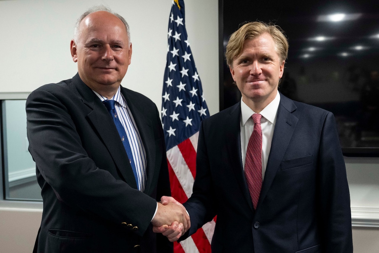 Two men in business attire shake hands.