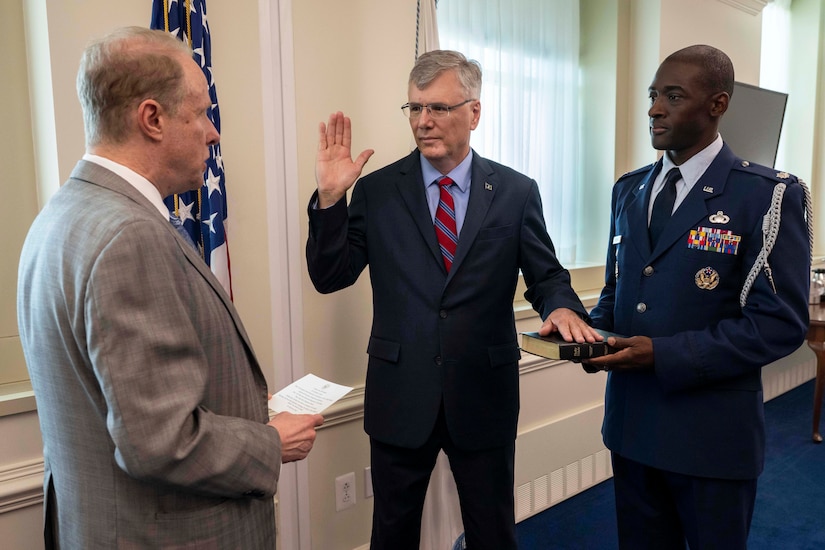 The Air Force secretary raises their right hand while placing the other on a Bible as the deputy defense secretary administers an oath.