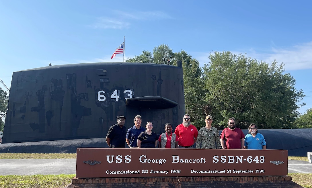 A group of people stand in front of the decommissioned submarine.