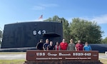 A group of people stand in front of the decommissioned submarine.