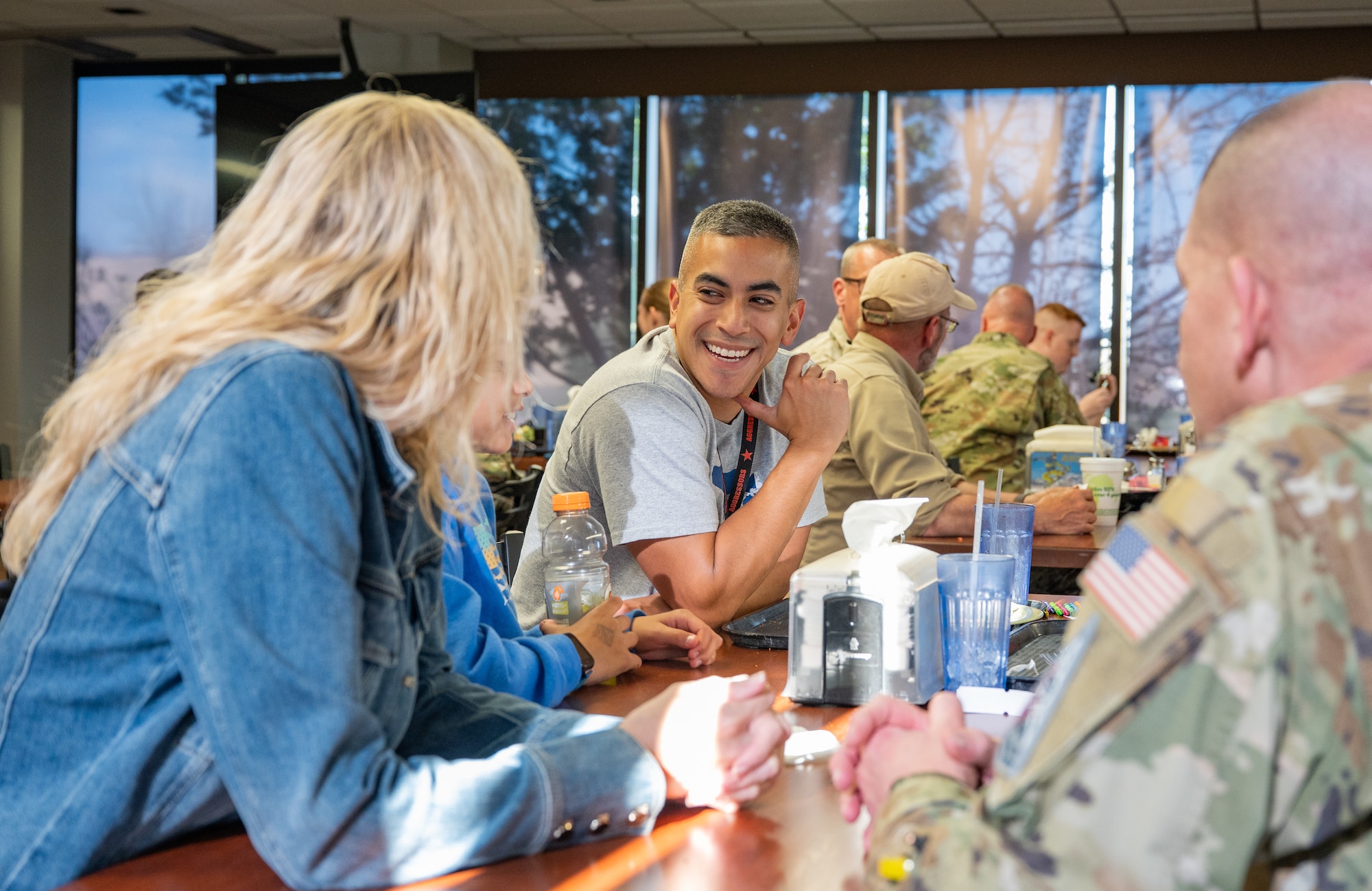 Service members and their families sit at a table and talk.