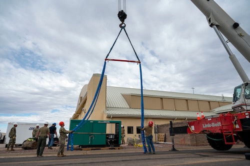 U.S. Airmen and civilians from the 355th Civil Engineer Squadron as well as Airmen from the Air Force Civil Engineer Maintenance Inspection and Repair Team and civilian contractors prepare to secure a new backup power generator to a 100-ton crane at Davis-Monthan Air Force Base, Arizona, May 13, 2025.