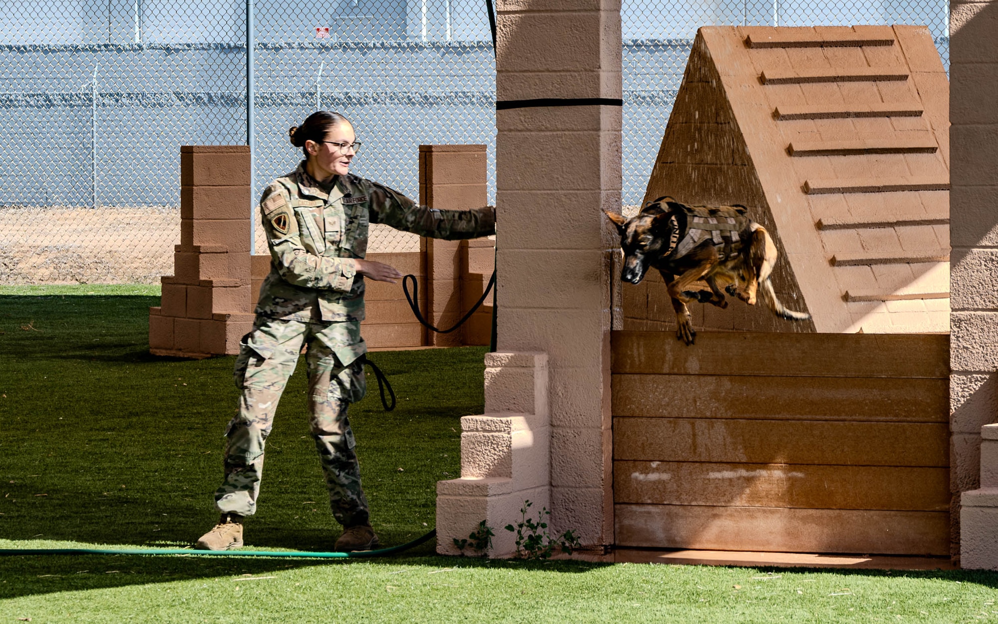 U.S. Air Force Senior Airman Julia Caccavo, 355th Security Forces Squadron military working dog handler, directs her K-9 partner, SSilke, to jump through a raining arch in an obstacle course during a police and military K-9 competition