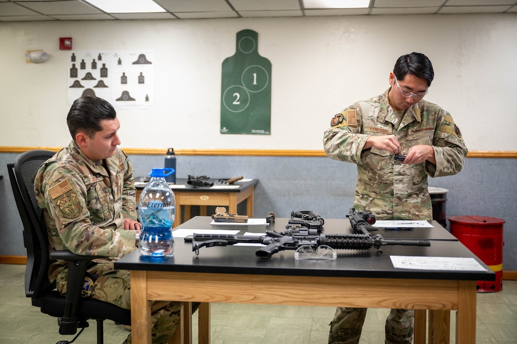 U.S. Air Force Staff Sgt. Alexander Juarez, 944th Security Forces Squadron defender, watches as Staff Sgt. Casey Kaneshiro, 309th Aircraft Maintenance Unit weapons load crew member, disassembles an M4 carbine during a manipulation competition for National Police Week, May 14, 2025, at Luke Air Force Base, Arizona.