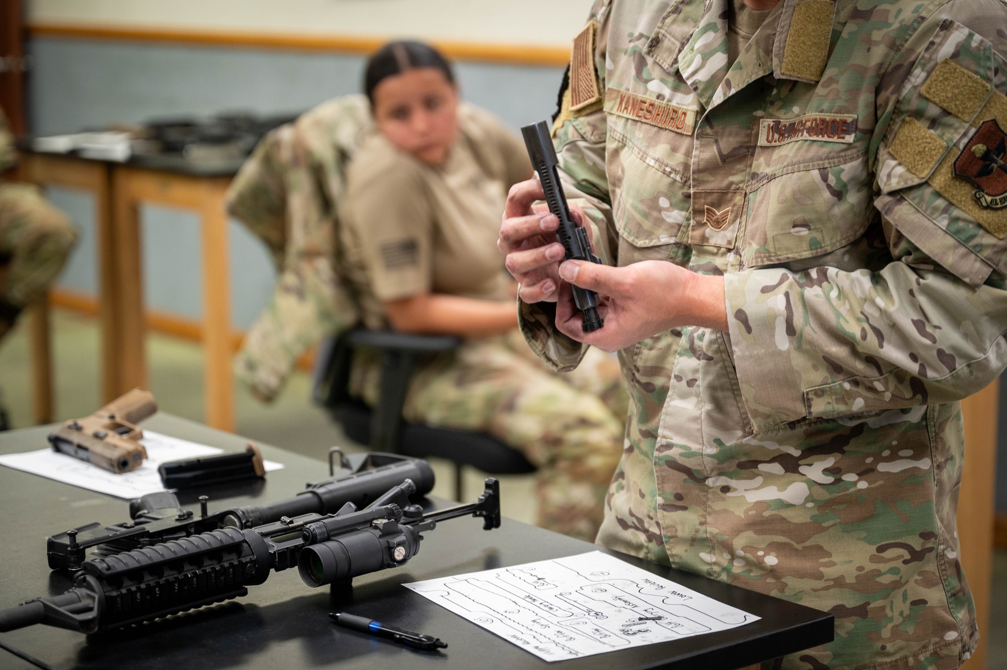Members of the 56th and 944th Security Forces Squadrons watch as U.S. Air Force Staff Sgt. Casey Kaneshiro, 309th Aircraft Maintenance Unit weapons load crew member, disassembles an M4 carbine during a manipulation competition for National Police Week, May 14, 2025, at Luke Air Force Base, Arizona.