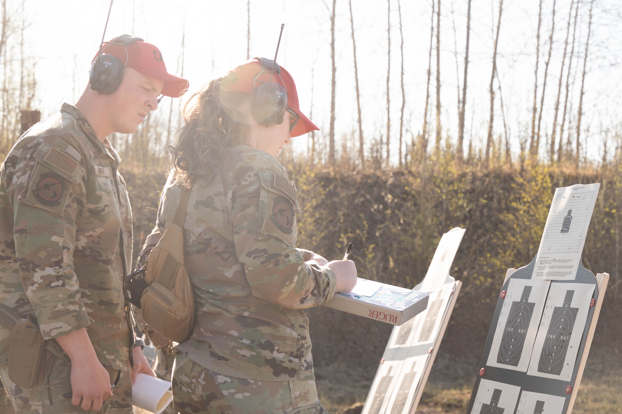 U.S. Air Force Staff Sgt. Brett Miner, left, 354th Security Forces Squadron combat arms training and maintenance trainer, and Senior Airman Megan Sheely Alvarado, 354th SFS CATM instructor, scores a participant's accuracy after an excellence in shooting competition at Eielson Air Force Base, Alaska, May 15, 2025.