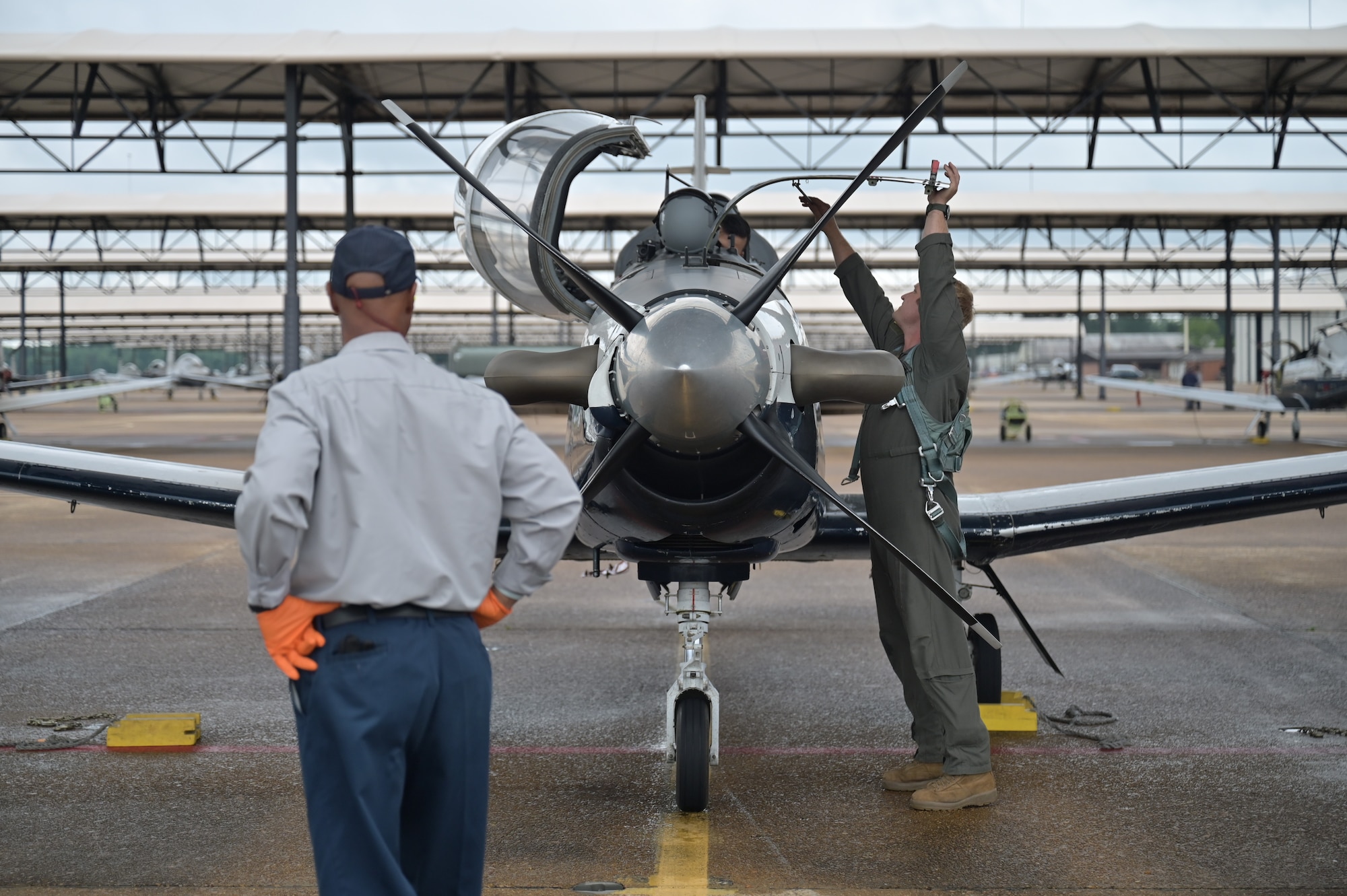 An M1 Support Services T-6A Texan II mechanic observes as an instructor pilot and student in Future Undergraduate Pilot Training (FUPT) perform final checks before flight.