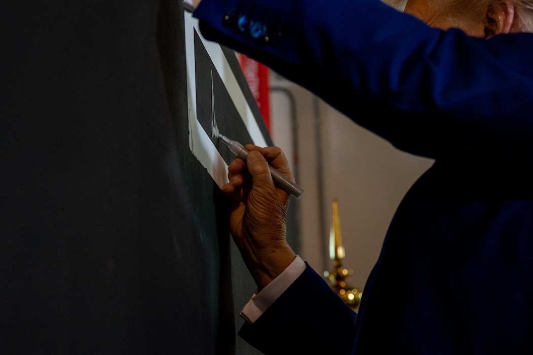 President Donald J. Trump signs a concrete T-Wall after meeting 379th Air Expeditionary Wing leadership, May 15, 2025. T-Walls, steel reinforced concrete blast walls, can be found throughout AUAB and squadrons often paint T-Walls to commemorate their deployments to AUAB. (U.S. Air Force photo by 1st Lt. Trevor Wood)