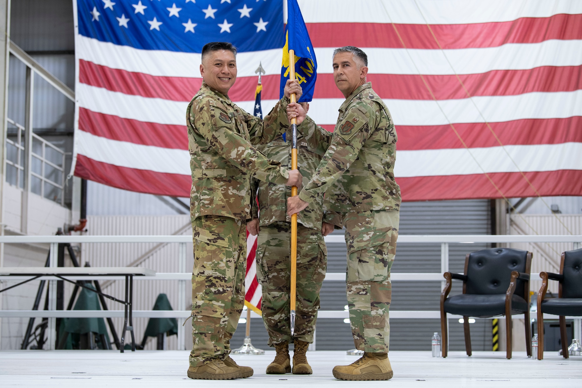Col. Van Thai, 434th Air Refueling Wing commander, passes on the guidon to Lt. Col. John Valdes in front of U.S. Flag