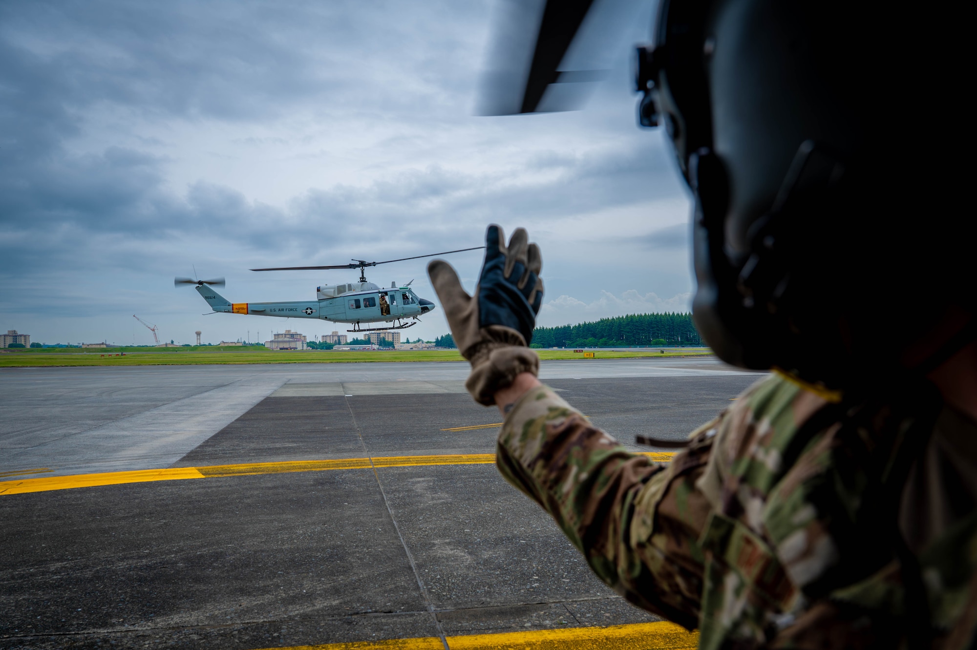 military member waving at a helicopter as it takes off